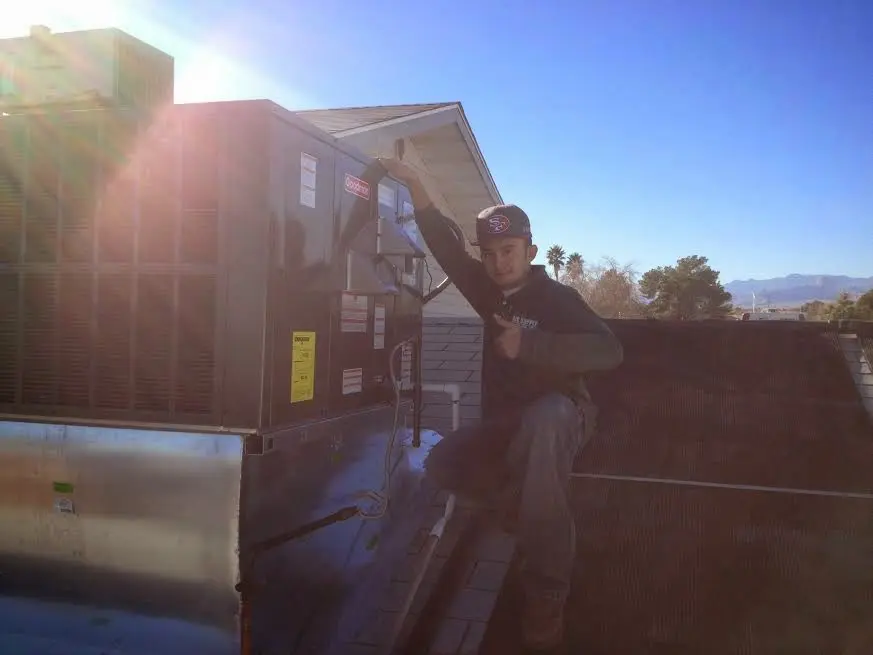 HVAC technician performing AC Tune-Up on a rooftop unit in Branford